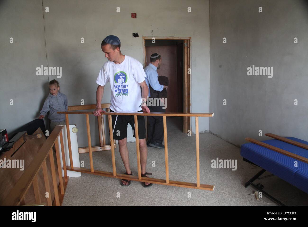 Hebron. 13th Apr, 2014. An Israeli settler moves furniture into a controversial four-story building in the West Bank city of Hebron, on April 13, 2014. Israel's Defense Minister Moshe Ya'alon on Sunday authorized Jewish settler families to move into a controversial building in the old city of Hebron in the West Bank, Israeli media reported. © Mamoun Wazwaz/Xinhua/Alamy Live News Stock Photo