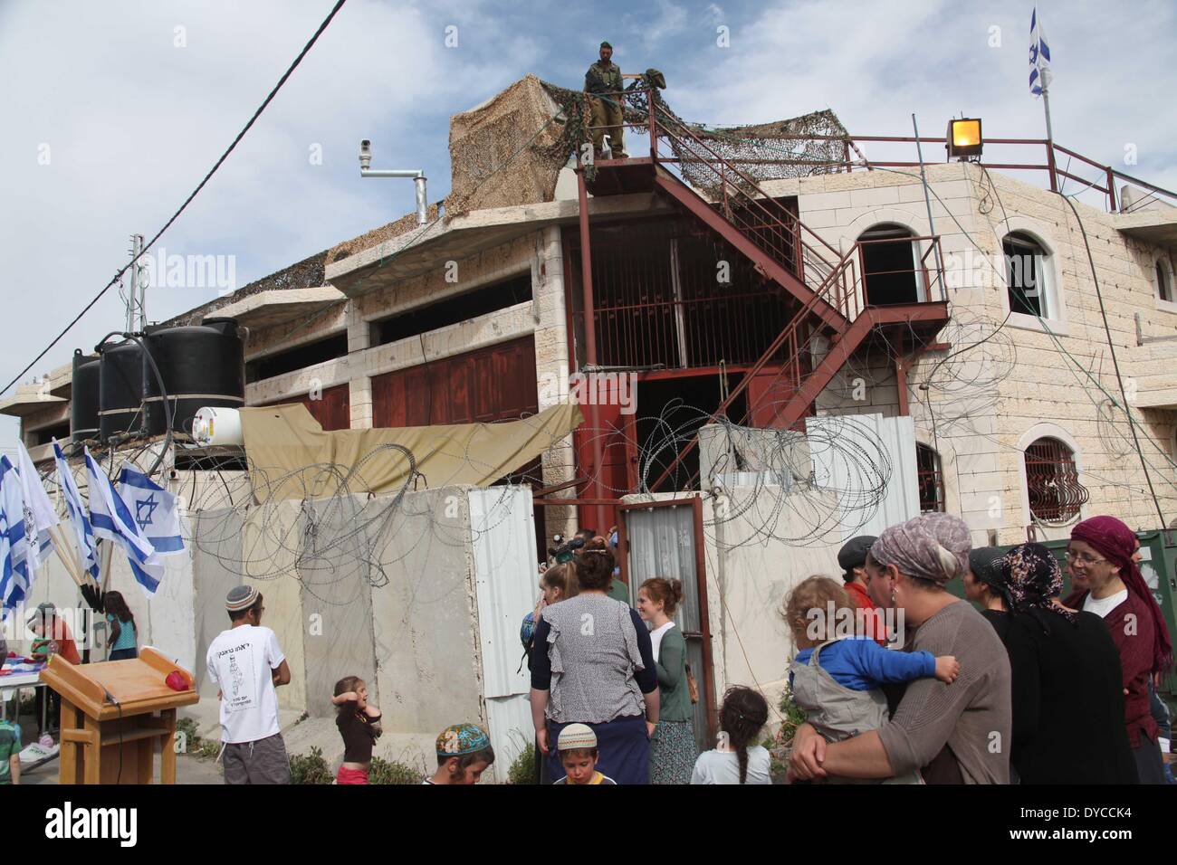 Hebron. 13th Apr, 2014. Israeli settlers wait to enter a controversial four-story building in the West Bank city of Hebron, on April 13, 2014. Israel's Defense Minister Moshe Ya'alon on Sunday authorized Jewish settler families to move into a controversial building in the old city of Hebron in the West Bank, Israeli media reported. © Mamoun Wazwaz/Xinhua/Alamy Live News Stock Photo