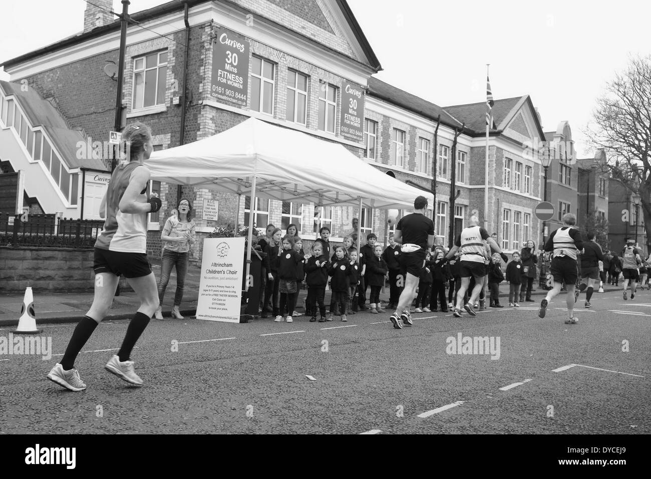 The 2014 Manchester Marathon: Runners reach Altrincham in Cheshire- Atrincham Children's Choir cheer the runners Stock Photo