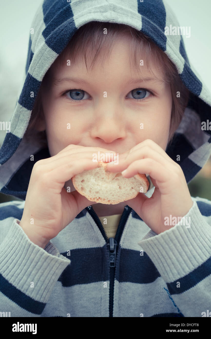 Young boy outdoors eating a piece of bread. Stock Photo