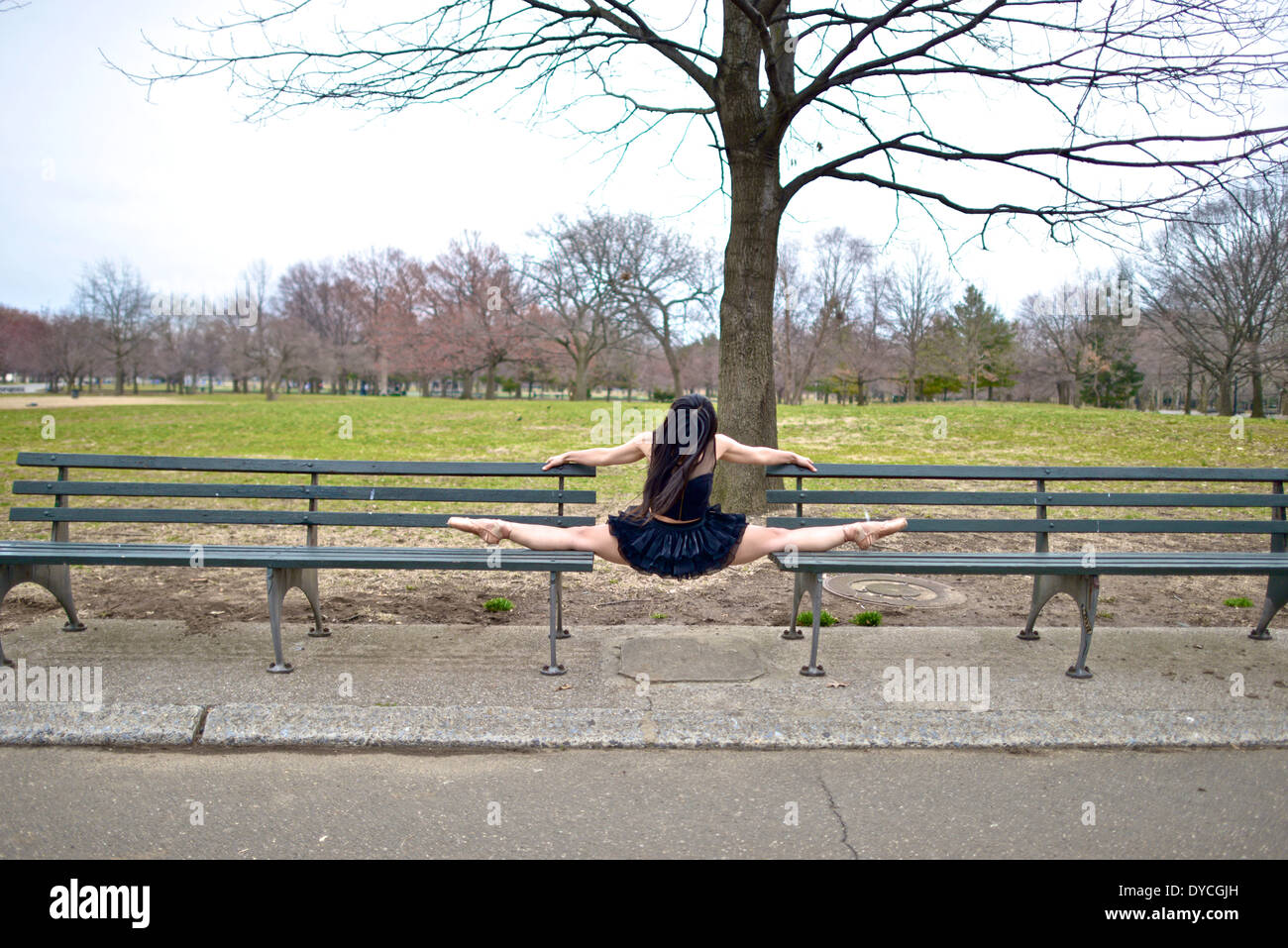 Asian ballerina wearing a black tutu balancing between two park benches Stock Photo