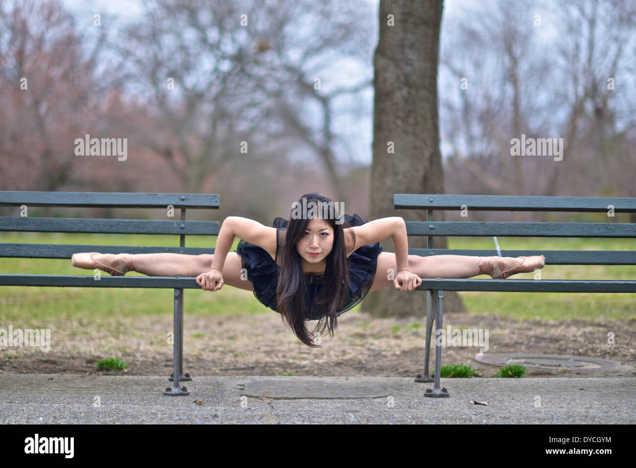 Asian ballerina wearing a black tutu balancing between two park benches Stock Photo