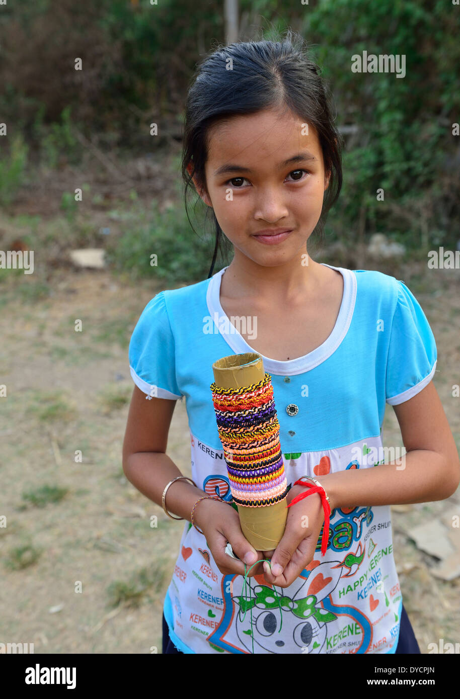 Young Cambodian girl offers her woven bracelets and rings.jewelry for sale to passengers from the Bamboo Train  O Sra Lav village, Cambodia Stock Photo