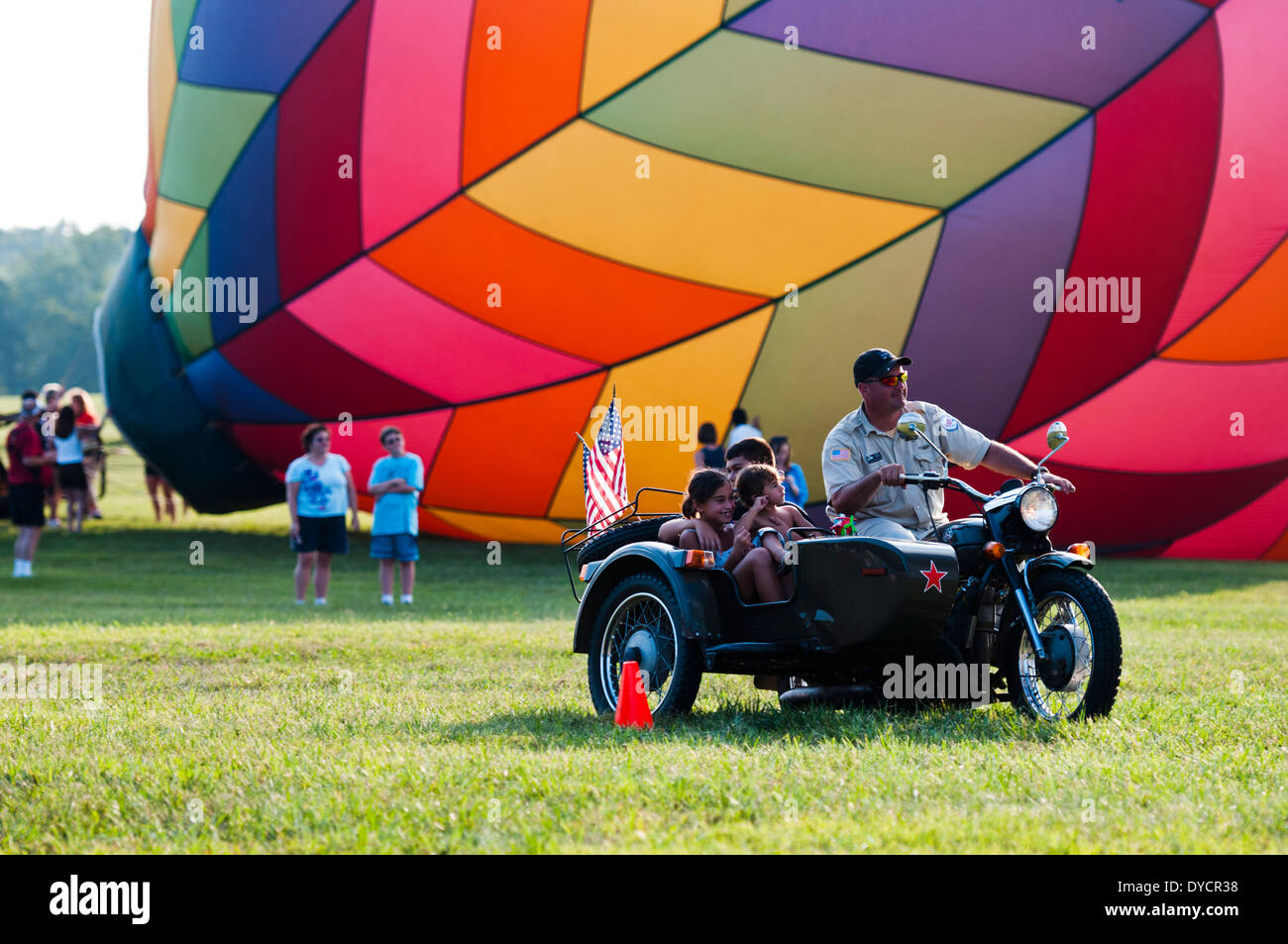 A man giving children rides on a vintage military motorcycle with sidecar at a hot air balloon festival in  Bealeton Virginia. Stock Photo