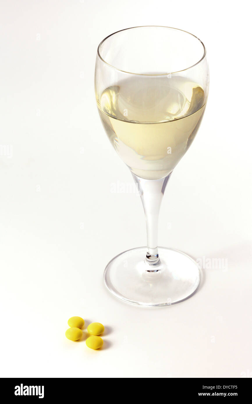 Drugs and alcohol interaction - glass of white wine and drug tablets, UK Stock Photo