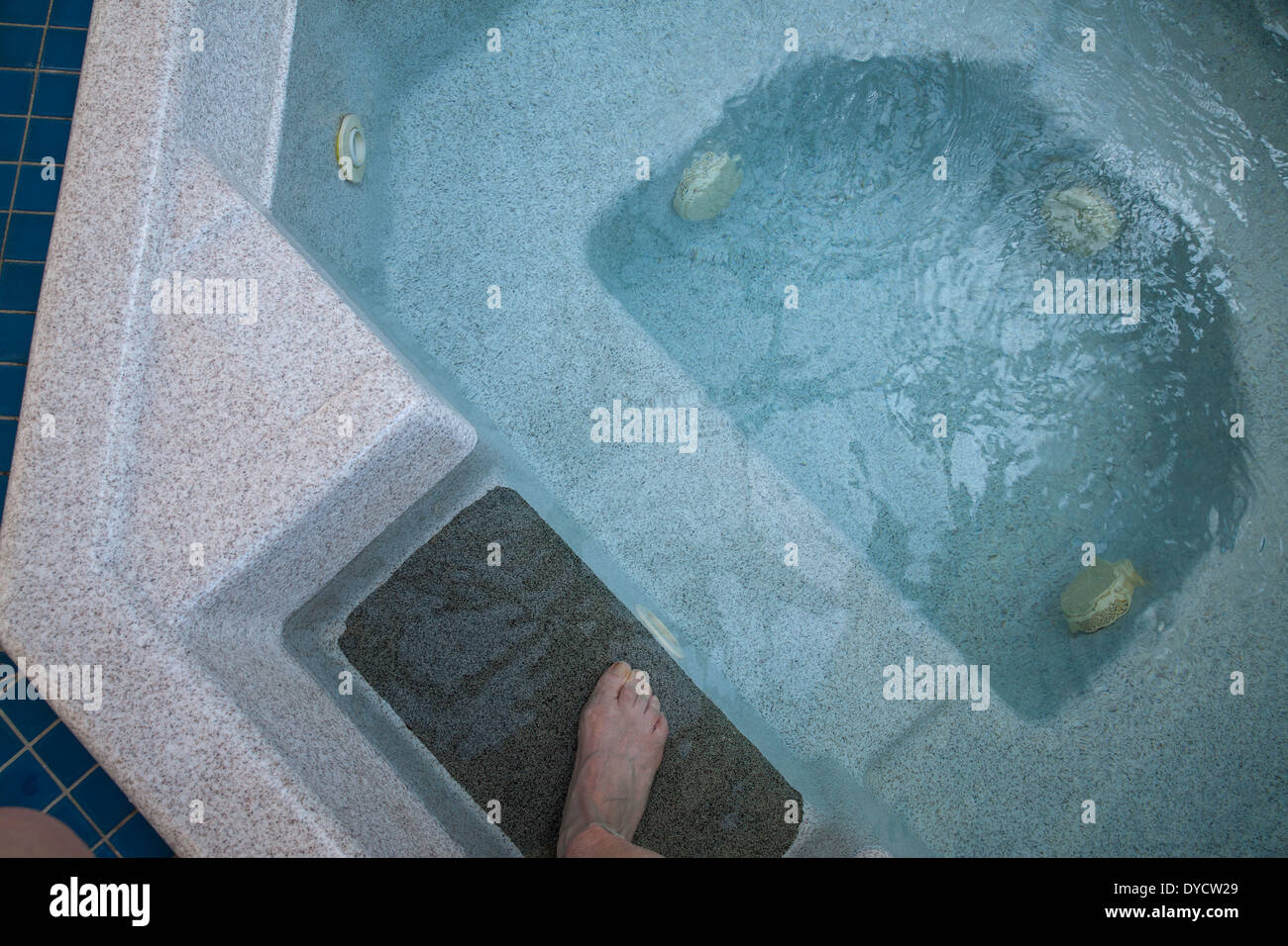 A  woman steps into a clear whirlpool. Stock Photo