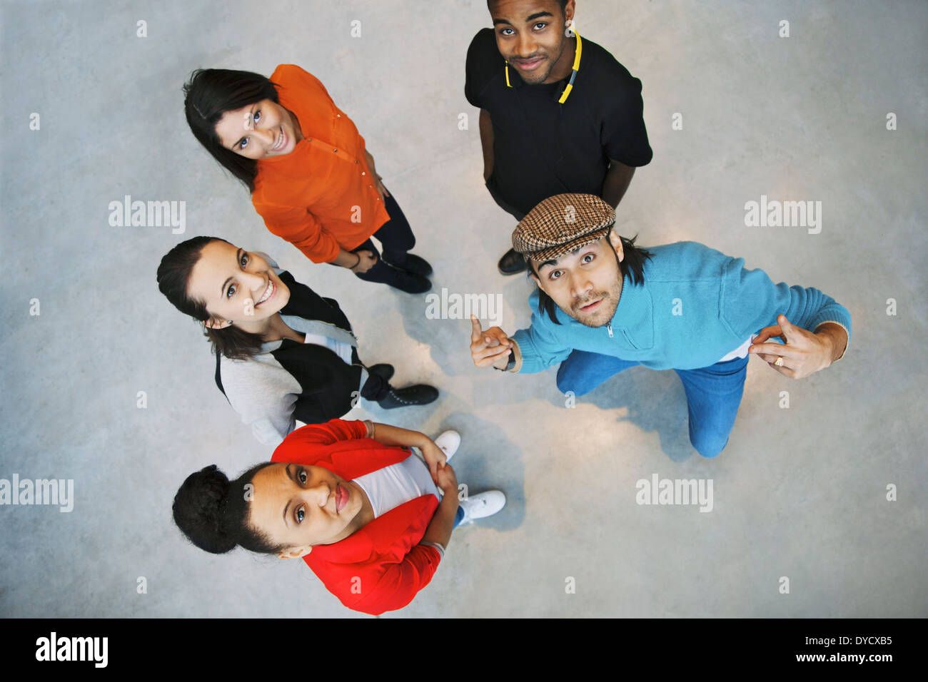 Overhead view of young people standing together looking up at camera with stylish young man gesturing. Team or group. Stock Photo