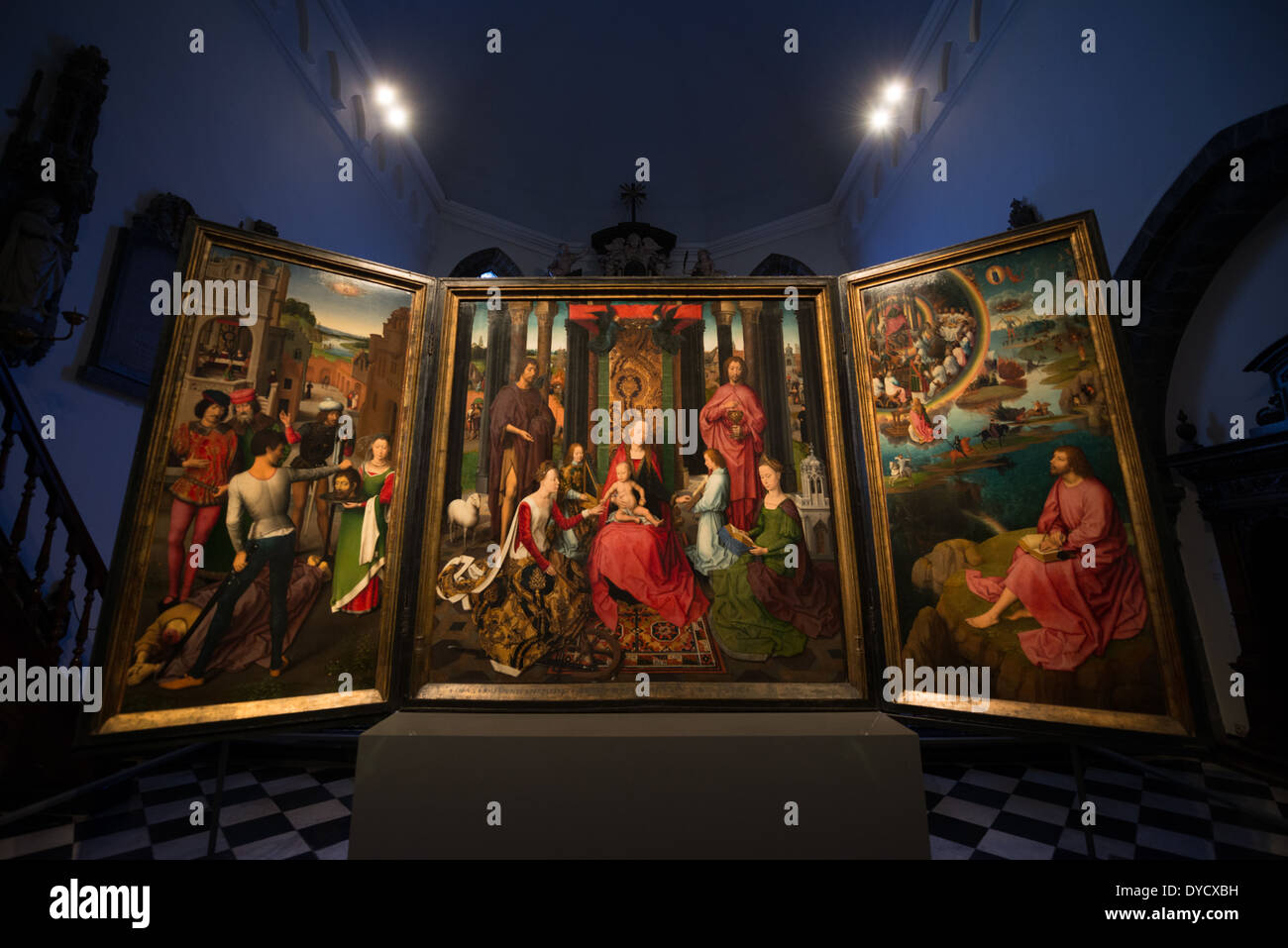 BRUGES, Belgium - Altar piece of John the Evangelist and John the Baptist. Hans Memling (c. 1430 - 1494) was commissioned to paint this triptych by the monastic community of the St John's Hospital. On the outside of the wings are the portraits of the donors--two monks and two nuns who held important offices in the foundation and who paid for this work. Depicted in the center of the panel is a 'Sacra conversazione', a gathering of saints and angels around the Virgin and Child. Both St. Barbara, who sits just in front of her tower, and St. Catherine, identified by her wheel, are closely associat Stock Photo