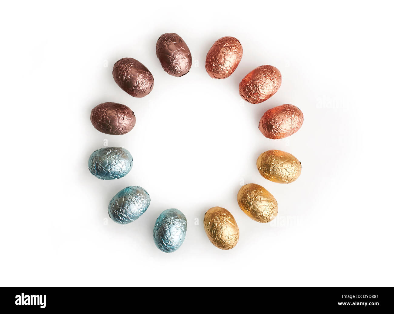 A circle of chocolate Easter Eggs wrapped in coloured tin foil on a white background. Stock Photo
