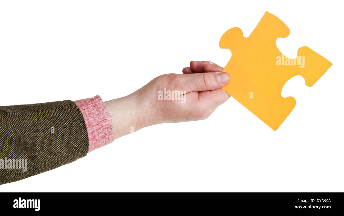 male hand holding big yellow paper puzzle piece isolated on white background Stock Photo
