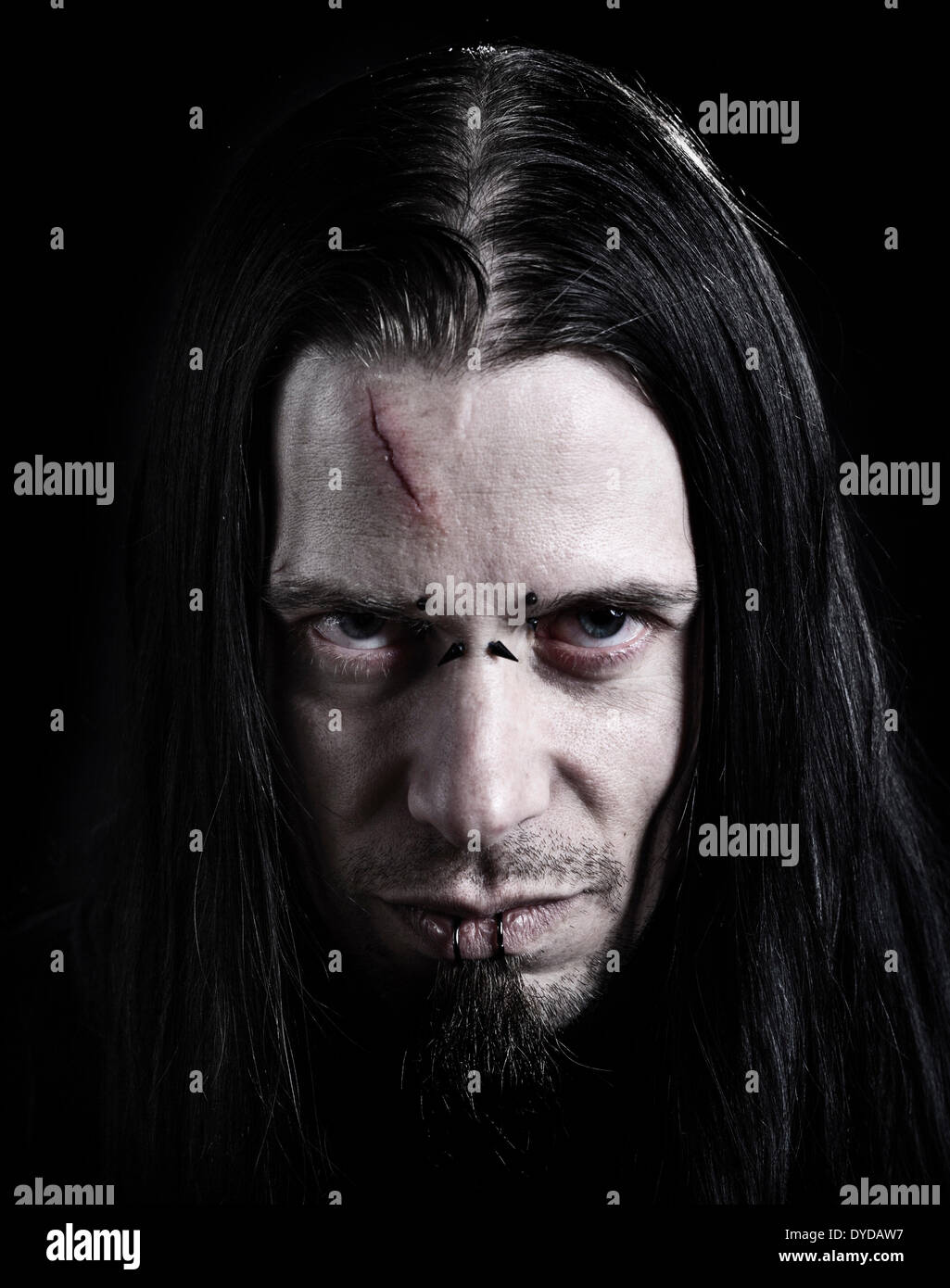 Man, 30-35, with a scar on his forehead, piercings and long black hair Stock Photo