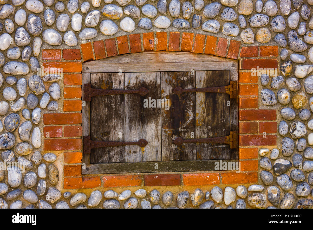 Shuttered window in brick and flint wall. Stock Photo