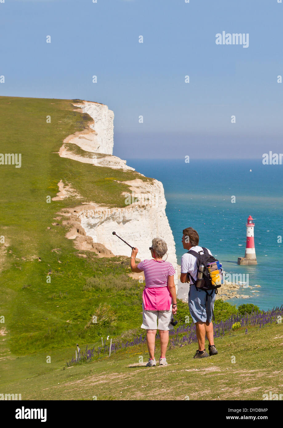Walkers on The South Downs Way at Beachy Head with Beachy Head Lighthouse out at sea. Stock Photo