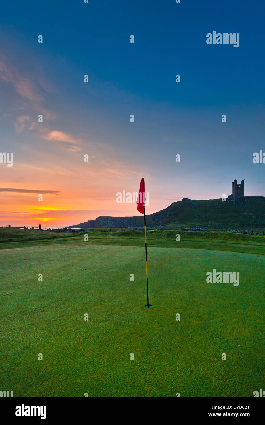 Dunstanburgh castle in Northumberland behind a green on the local golf course. Stock Photo