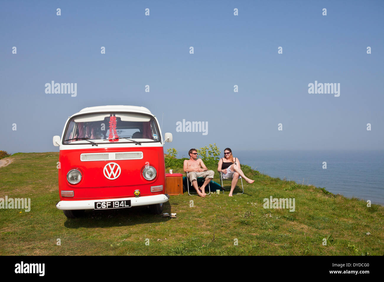 A young couple camping in a VW campervan on the clifftops over Mundesley on the Norfolk coast. Stock Photo