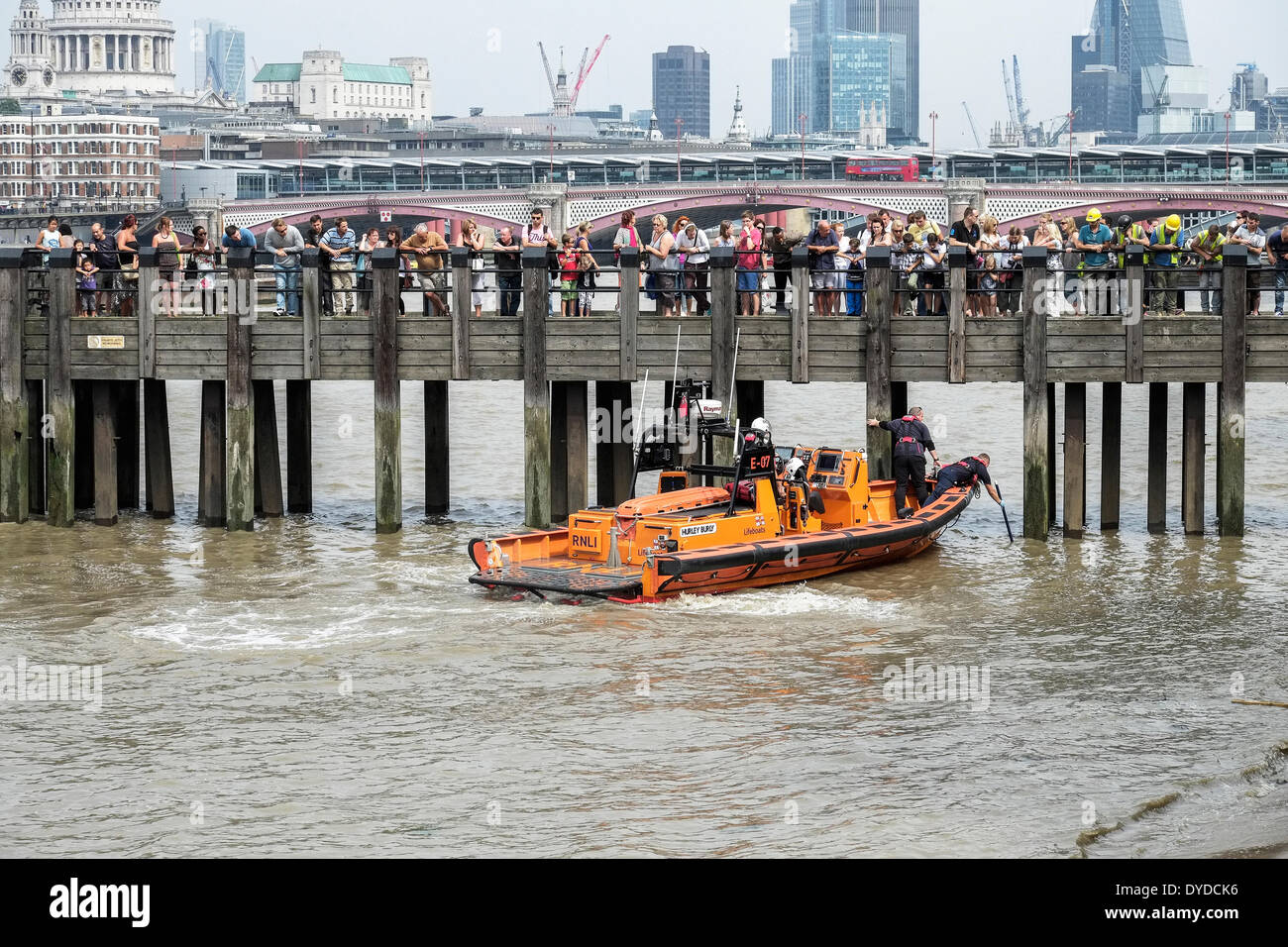 Members of the public watch the crew of the RNLI boat Hurley Burly search the River Thames for a body. Stock Photo