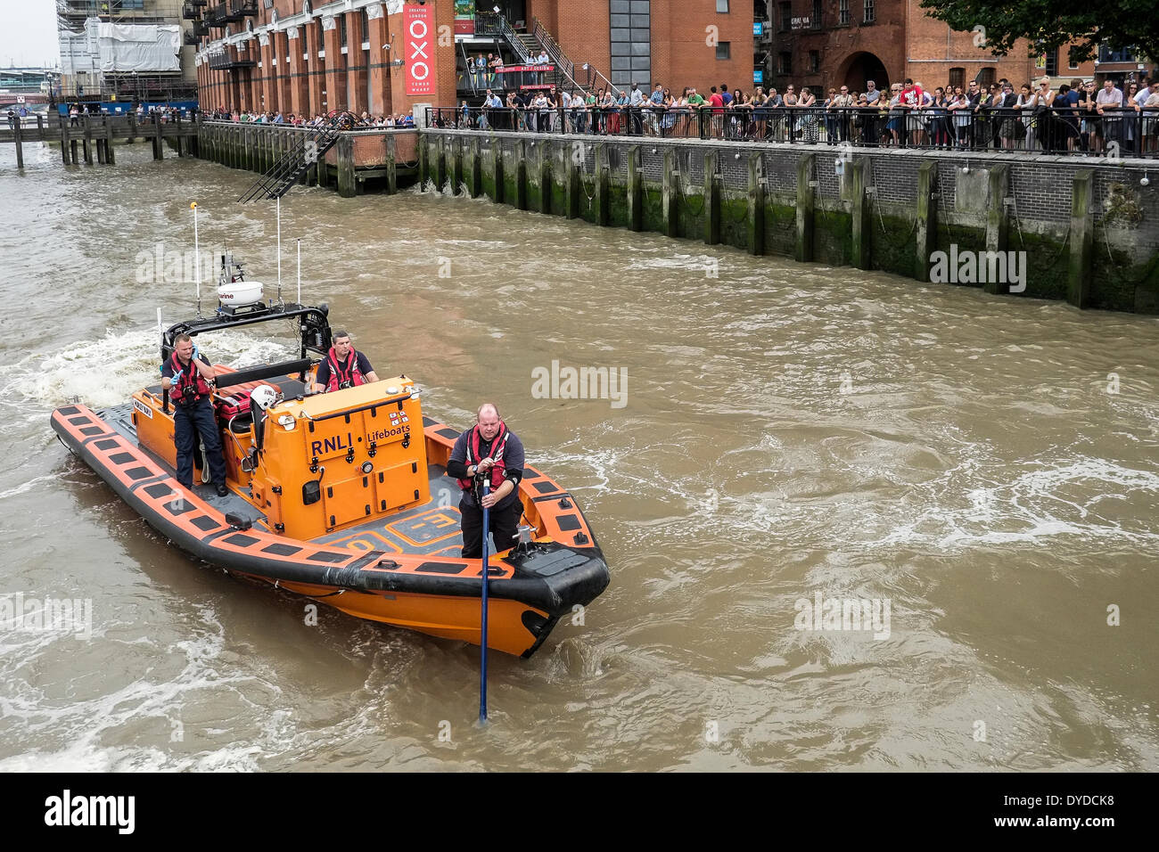 The public look on as the crew of the RNLI boat Hurley Burly search the River Thames for a body. Stock Photo