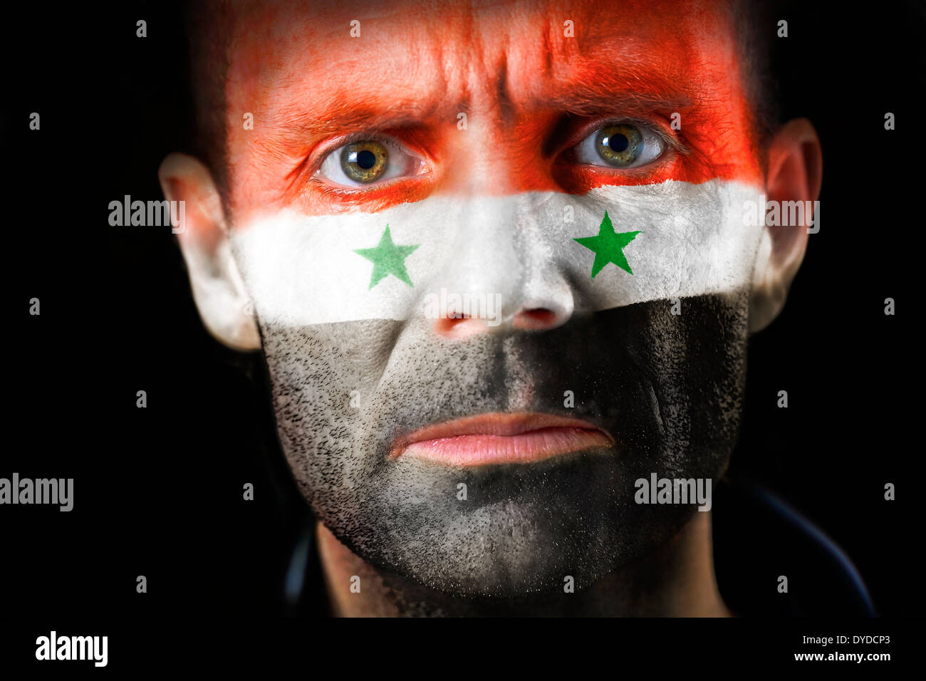 An intense stare from a man with their face painted with the Syrian flag. Stock Photo