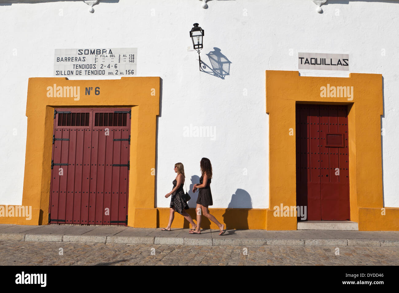 Two young women walk by the Plaza de toros de la Real Maestranza. Stock Photo