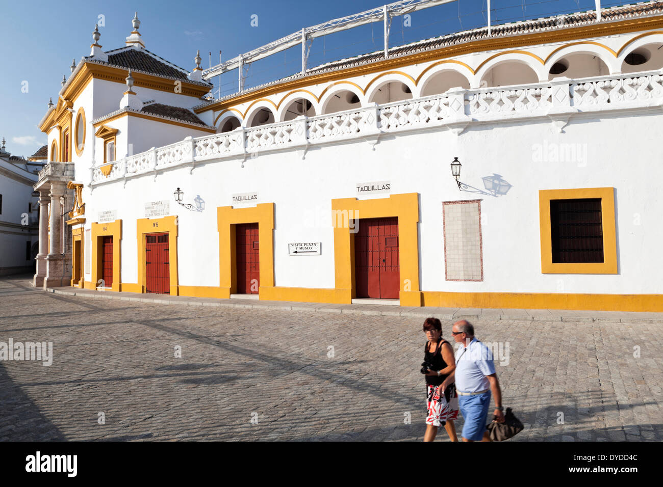 Tourists walk by the Plaza de toros de la Real Maestranza. Stock Photo