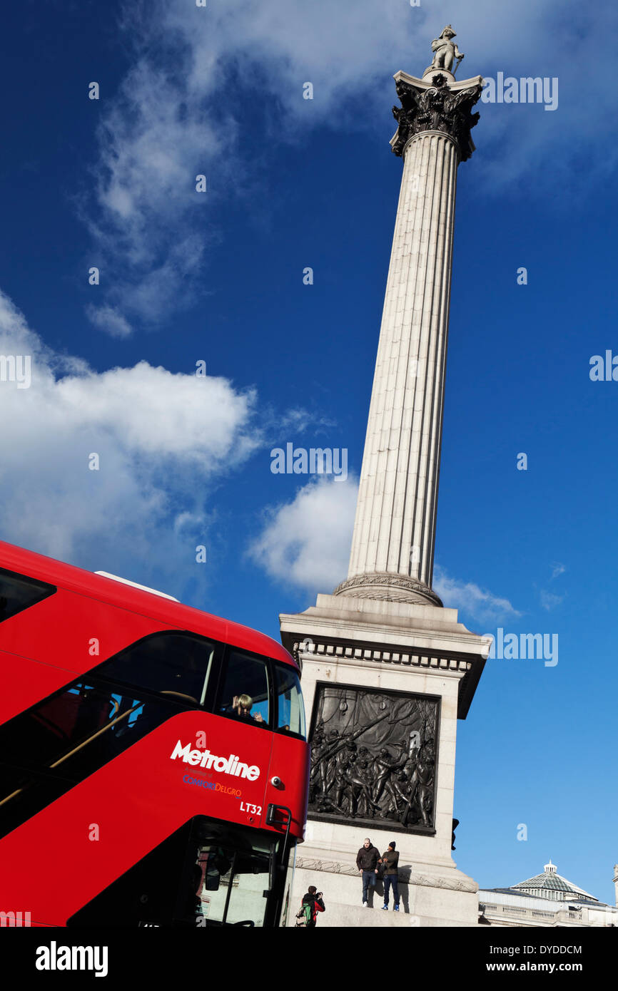 A red London bus passes Nelson's Column. Stock Photo