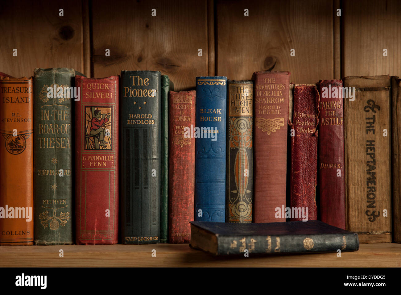 Vintage hardback books on a wooden bookshelf. Stock Photo