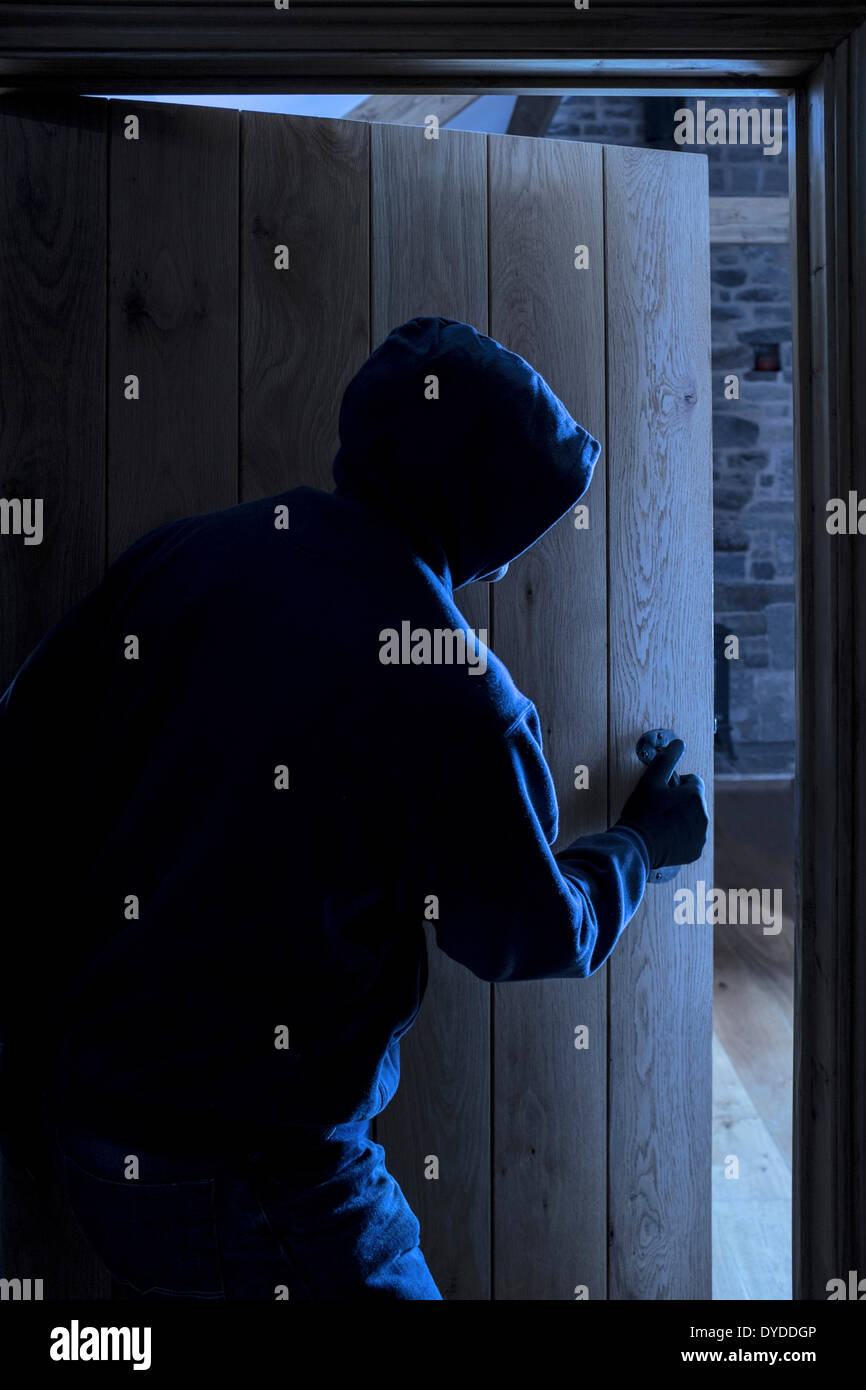 An anonymous hooded male entering a room. Stock Photo