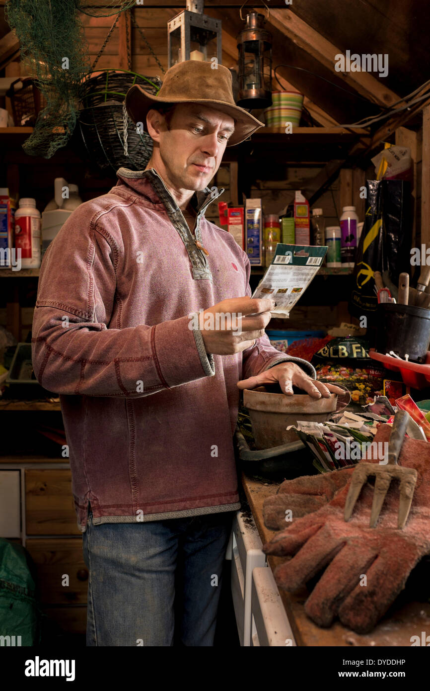 Man with a packet of seeds in his garden shed. Stock Photo