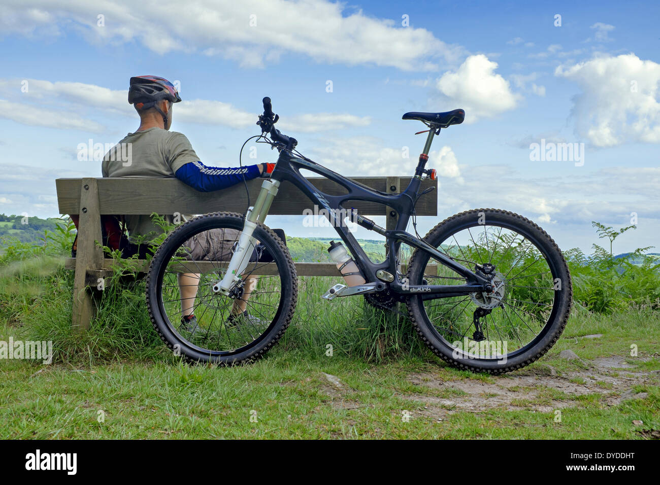 Male mountain biker resting on a wooden bench. Stock Photo