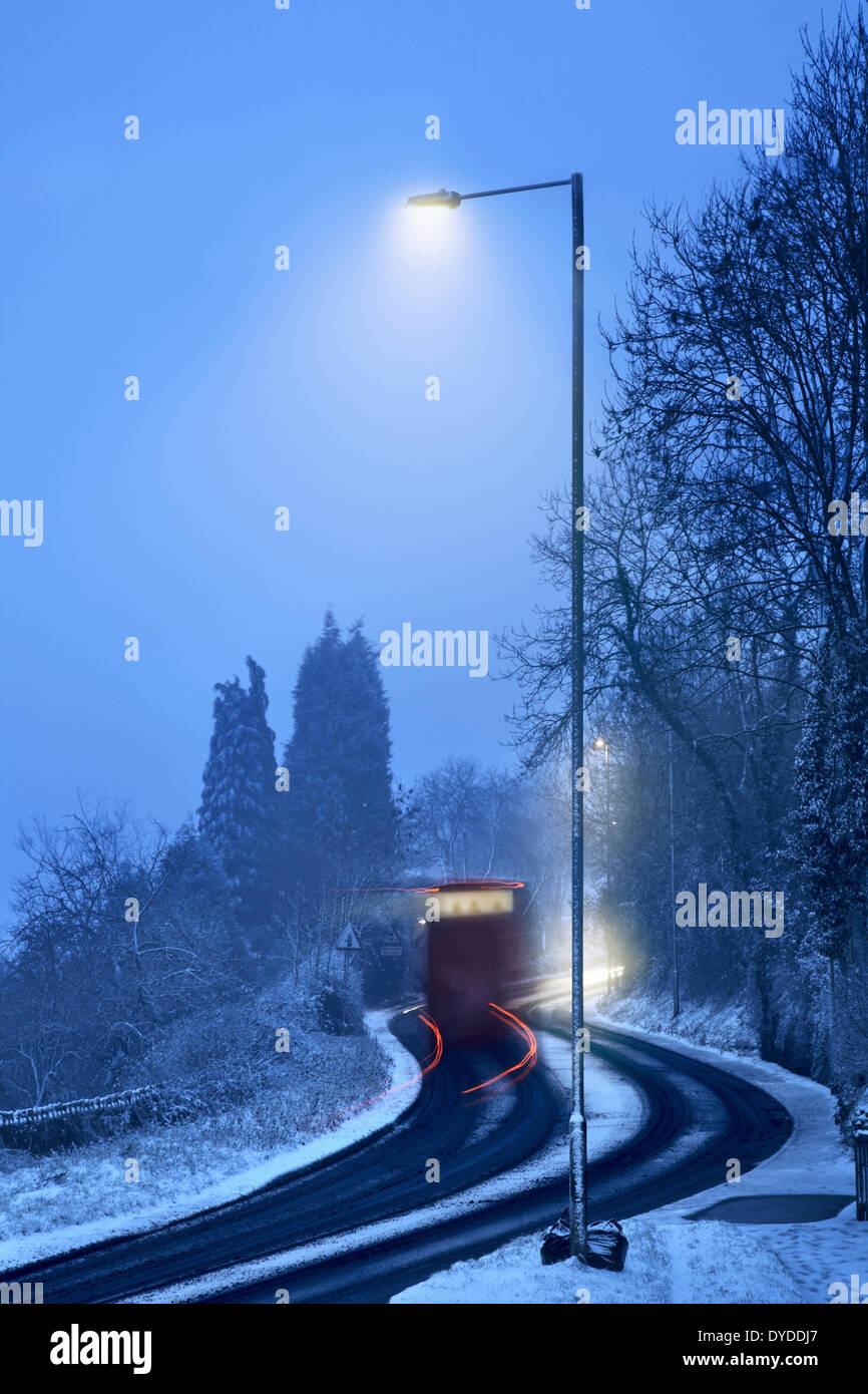 Bus carrying passengers along a snowy road. Stock Photo