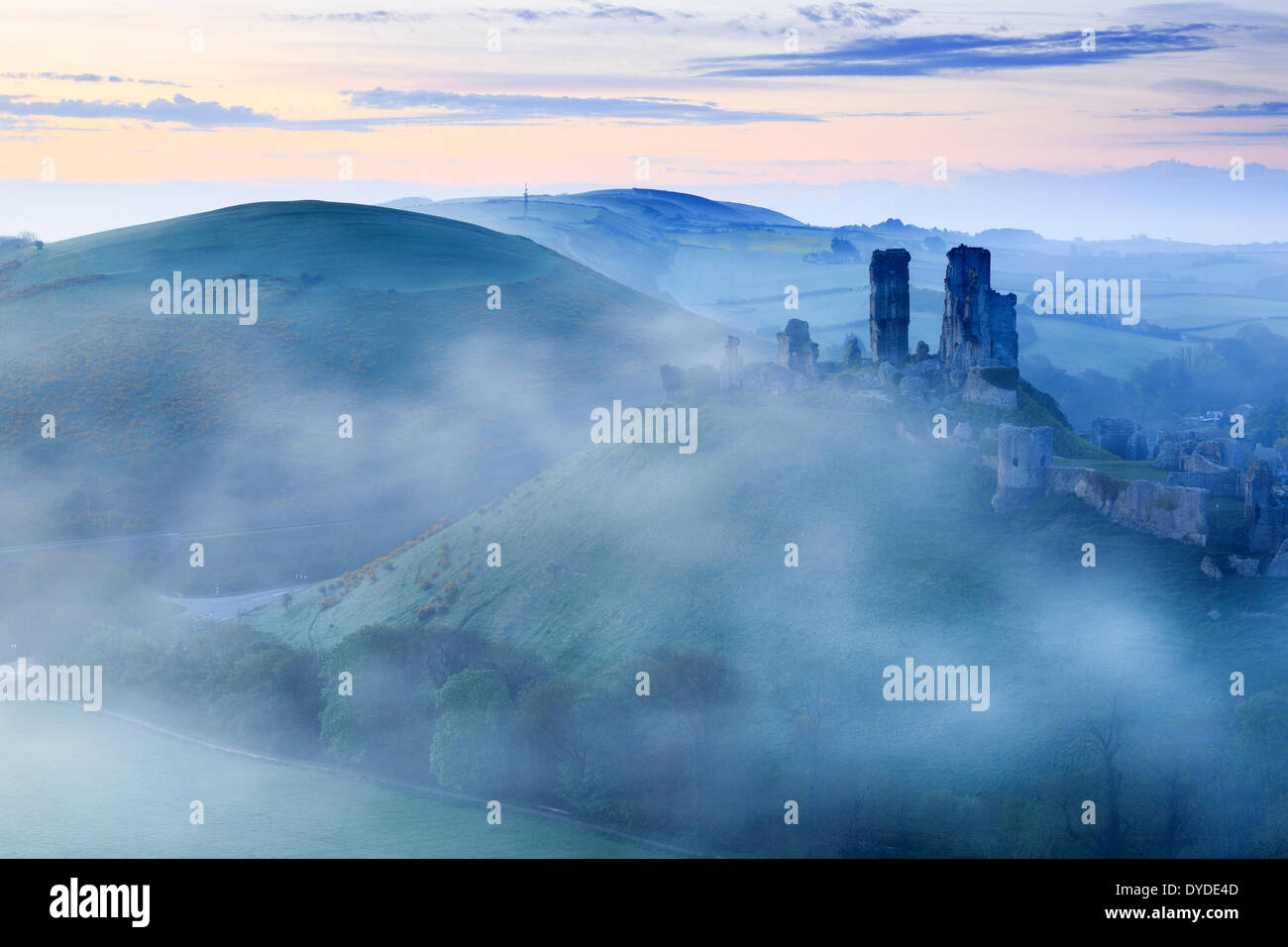 Corfe Castle in Dorset rising above early morning mist. Stock Photo