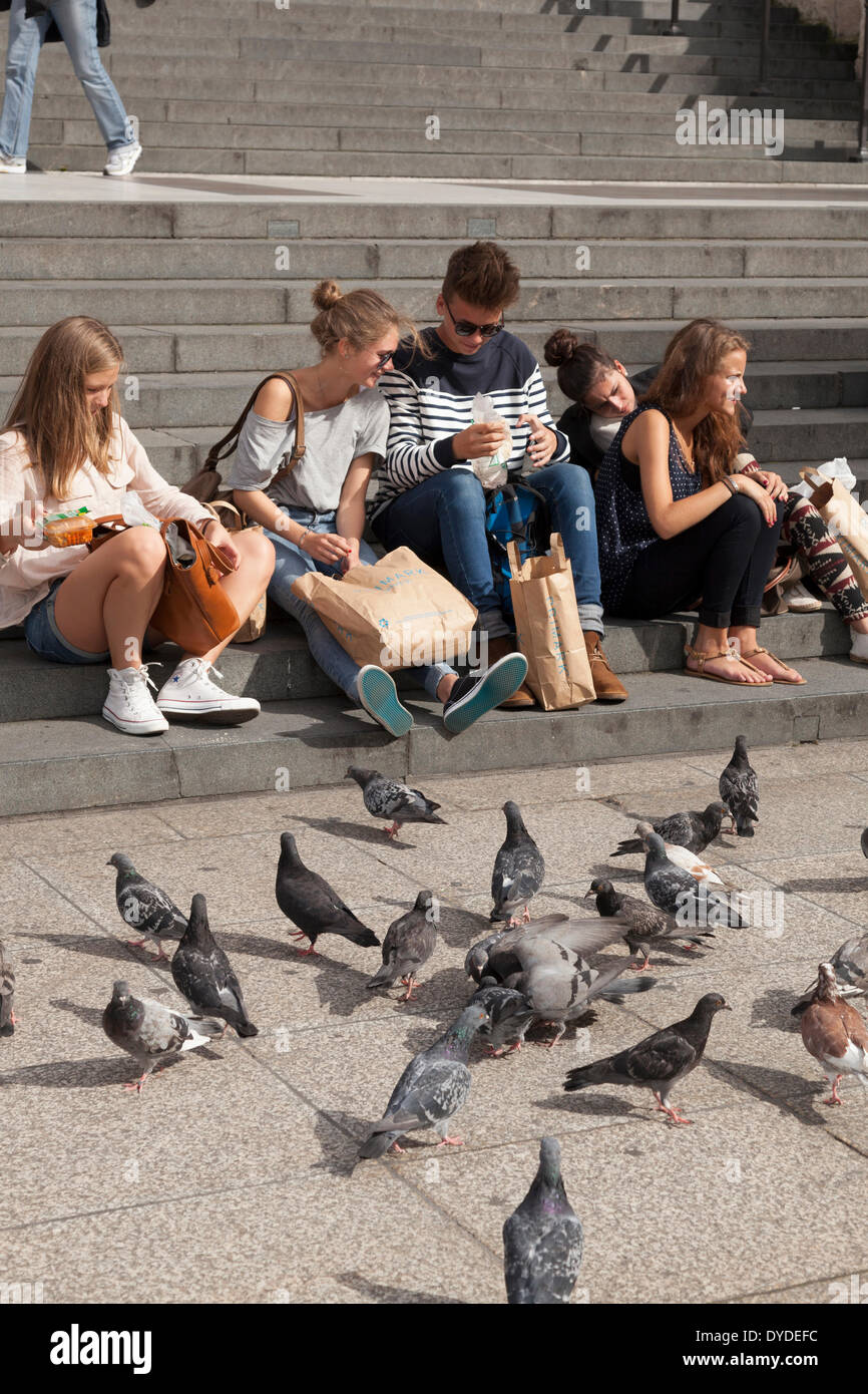 Tourists feeding the pigeons on the steps of St Paul's Cathedral in London. Stock Photo