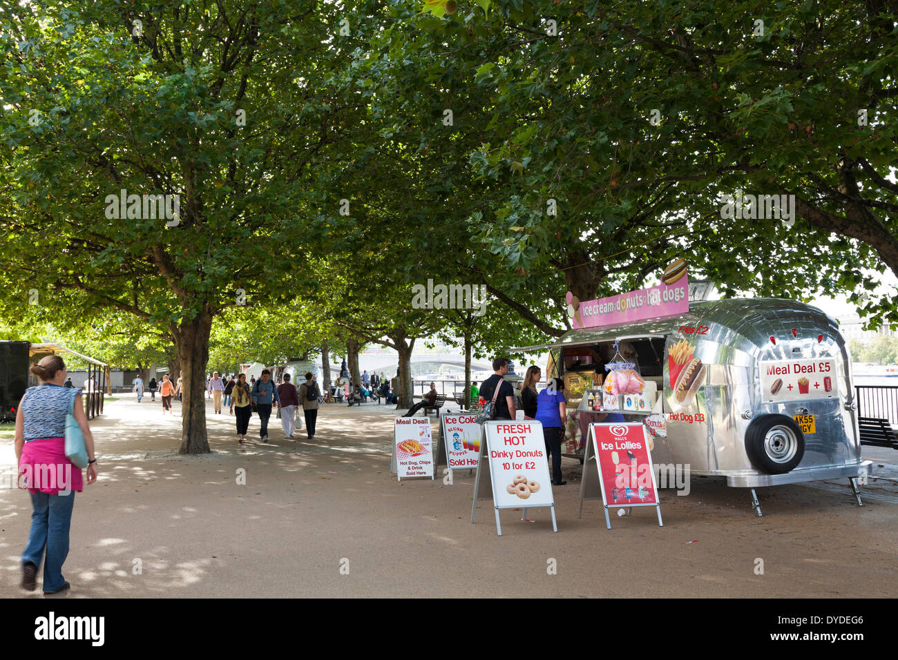Ice cream and donut van under the trees on the South Bank of the Thames in London. Stock Photo
