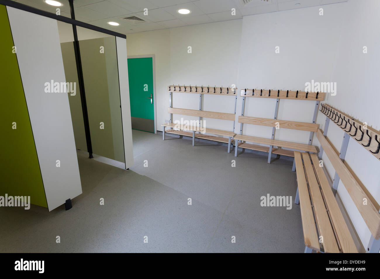 Unoccupied school changing room with benches and cubicles. Stock Photo