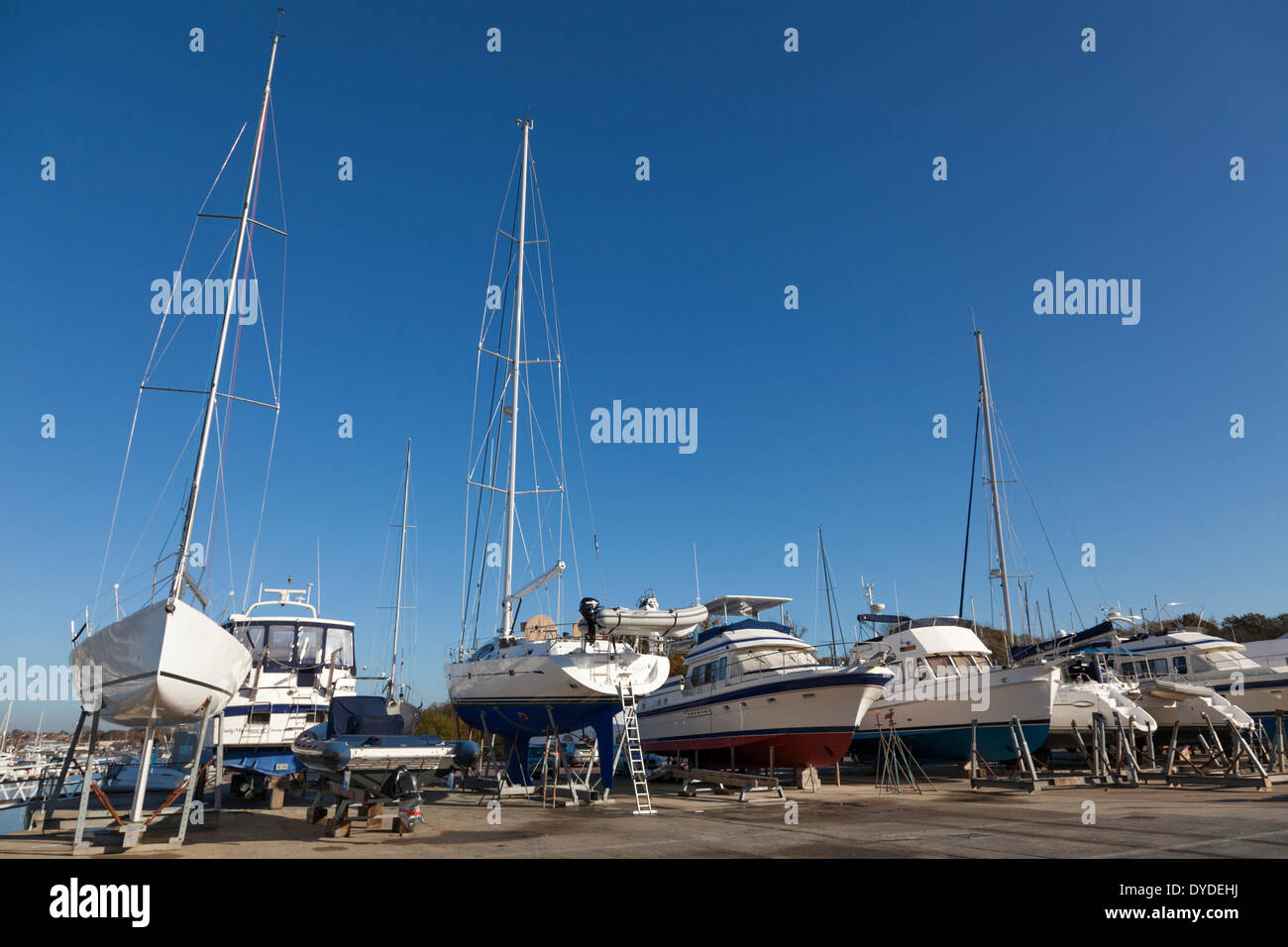 Yachts and motor crusiers on props in a boatyard out of the water for the winter. Stock Photo