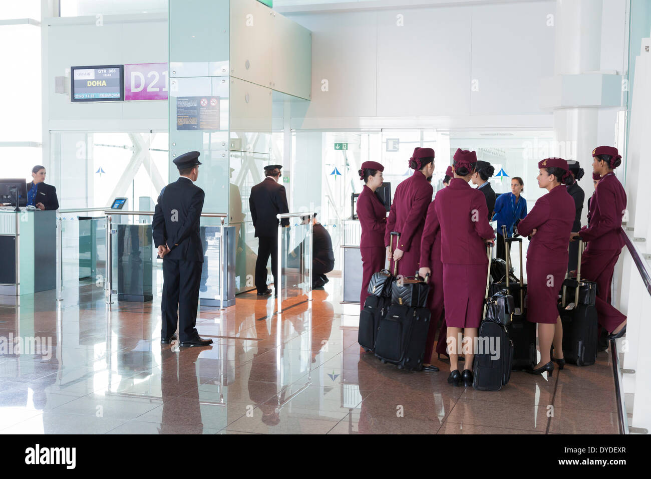 Qatar airways pilots and cabin staff waiting at airport departure gate