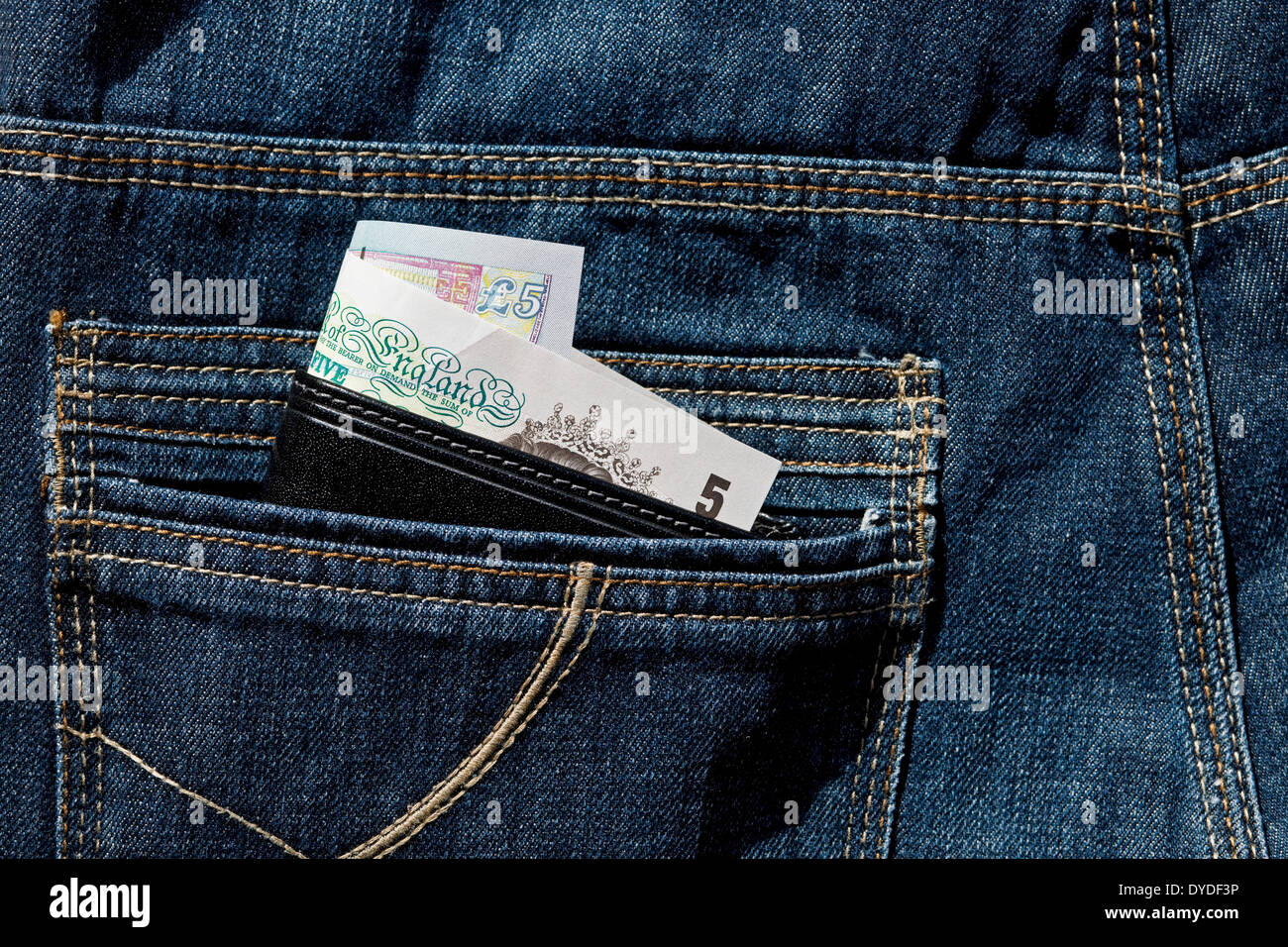 Leather wallet showing English banknotes in the back pocket of jeans. Stock Photo