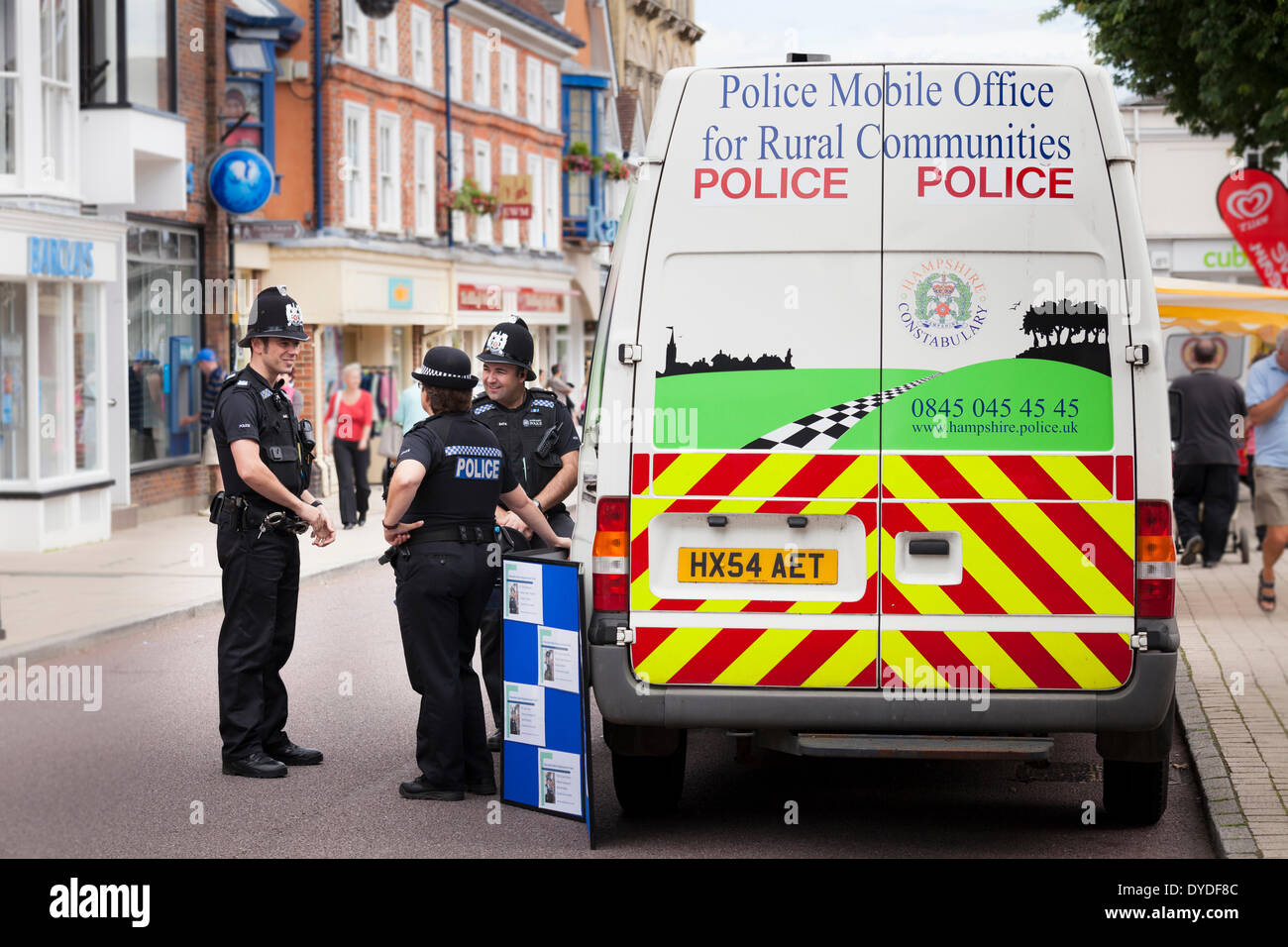 Policemen and women by police rural communities mobile office van in town high street. Stock Photo