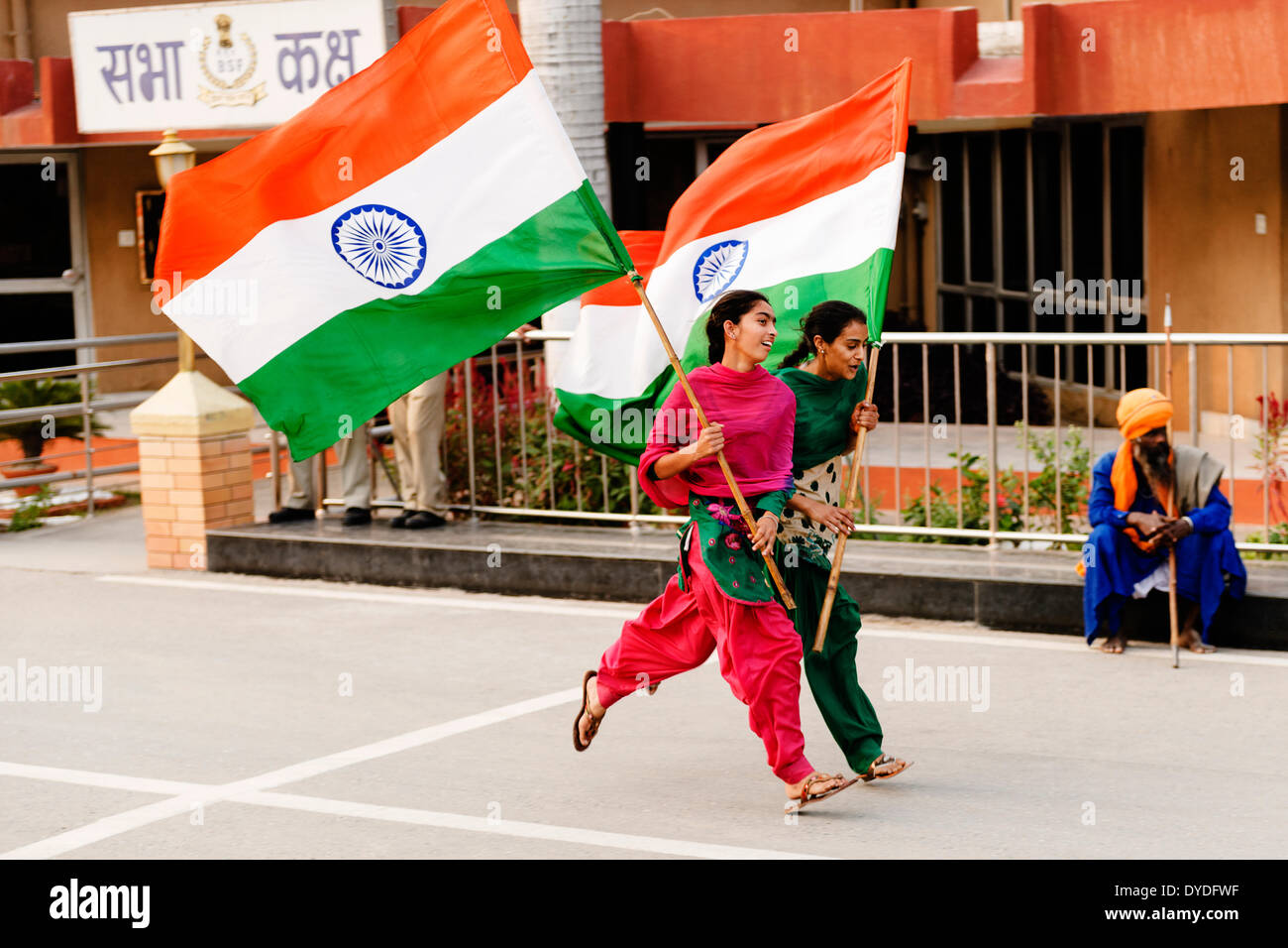 Two young women running waving the Indian Flag at the India and Pakistan border changing of the guards ceremony. Stock Photo