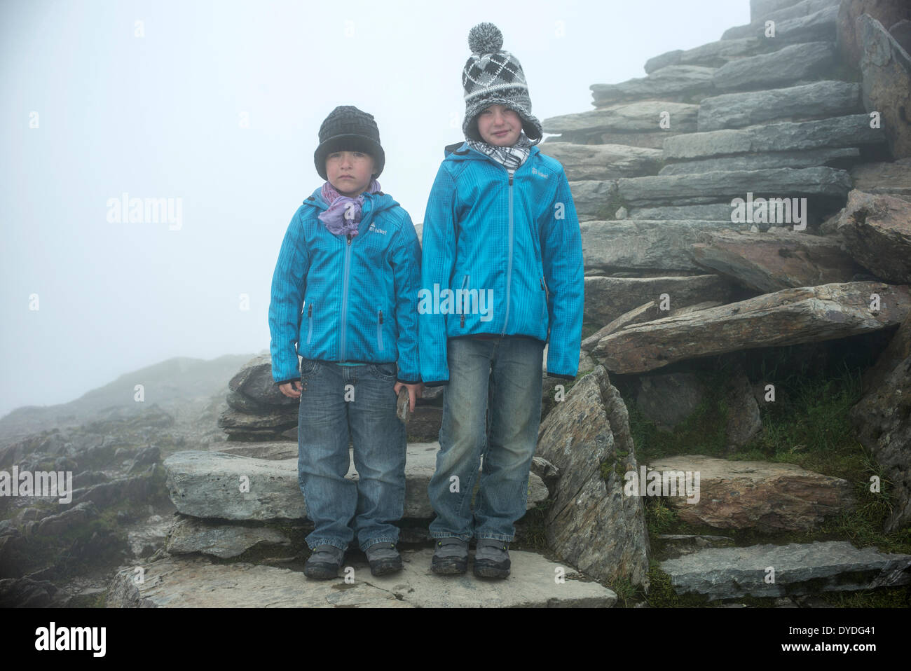 Two grumpy boys reach the summit of Mt Snowdon in a cloud. Stock Photo