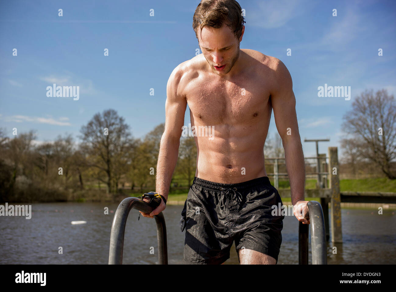A young man in swimming trunks next to spring fresh water ponds. Stock Photo