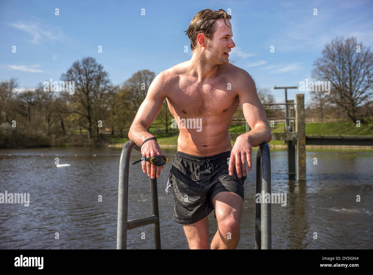 A young man in swimming trunks next to spring fresh water ponds. Stock Photo