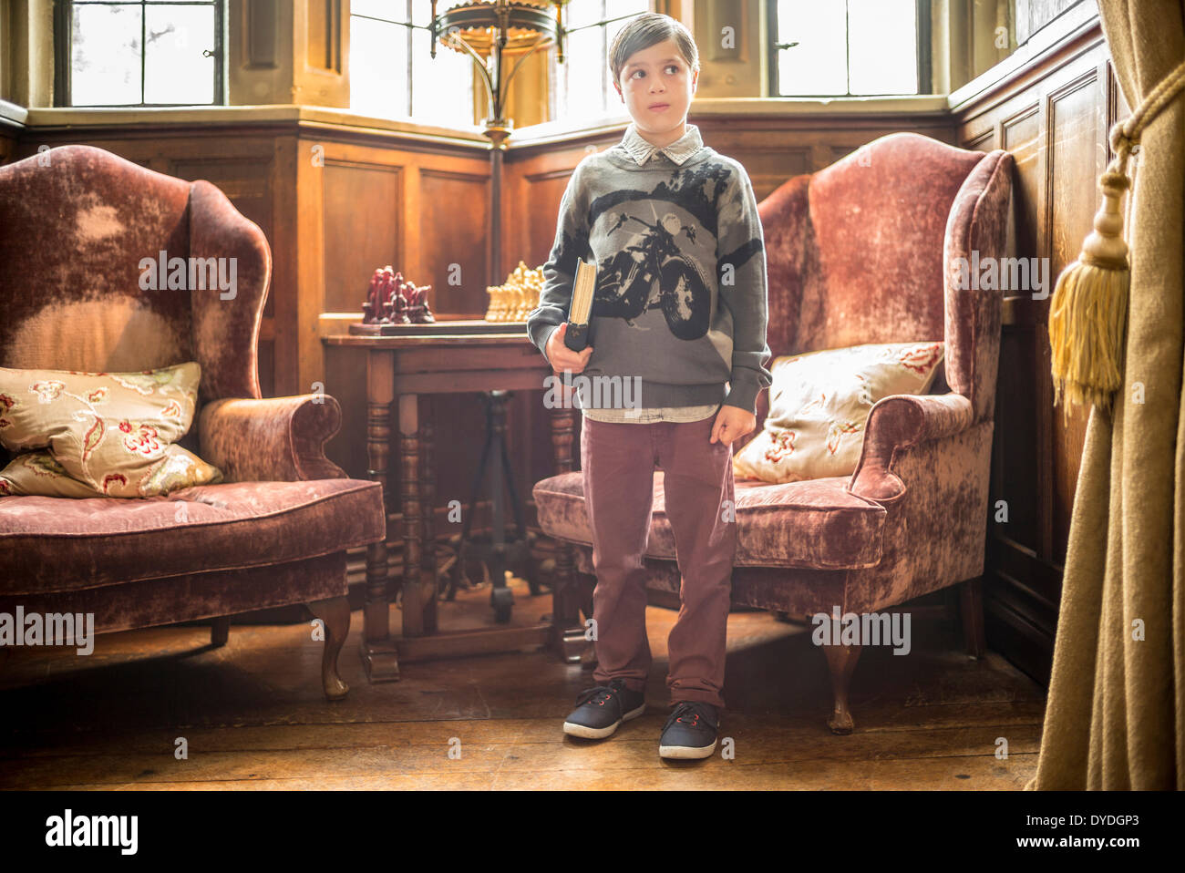 A young boy standing with a book under his arm in Thornbury Castle. Stock Photo