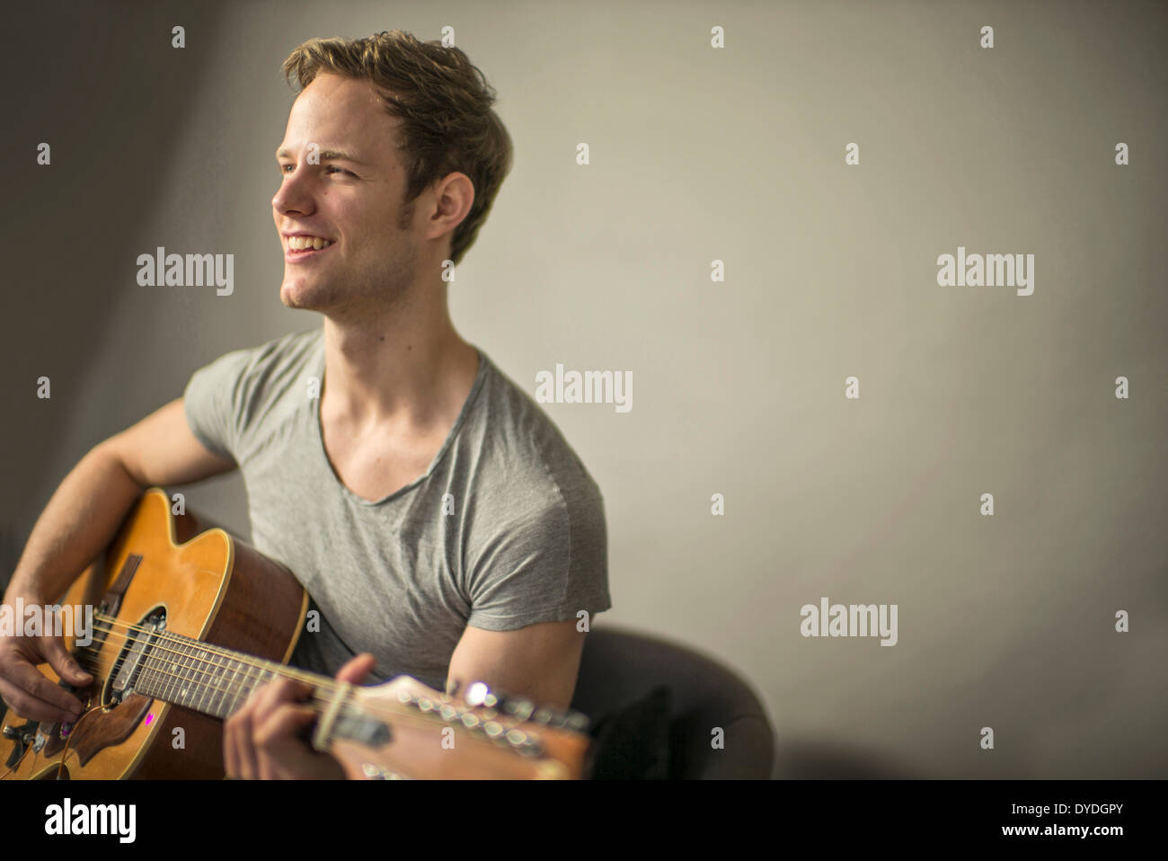 A beautiful young man playing acoustic guitar. Stock Photo