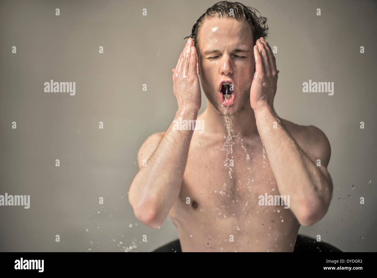 A beautiful young man splashing water on his face. Stock Photo