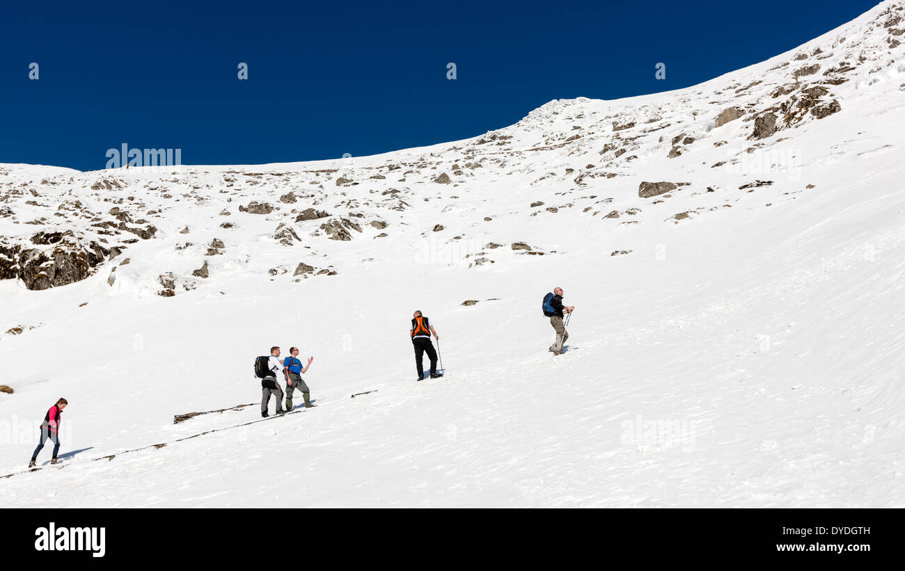 A group of people climbs the snowy Pyg Track in the Snowdonia National Park. Stock Photo