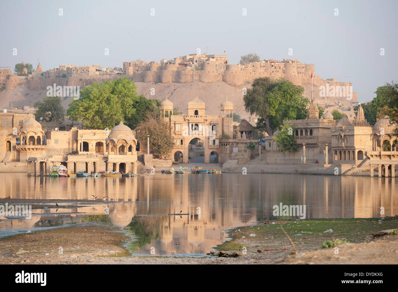 Gadi Sagar, Jaisalmer, Rajasthan, India. 15th April, 2014. 6.00 AM and the buildings surrounding the Gadi Sagar lake and the Jaisalmer Fort in the distance are already drenched in the Rajasthani sun's golden rays. Credit:  Lee Thomas/Alamy Live News Stock Photo