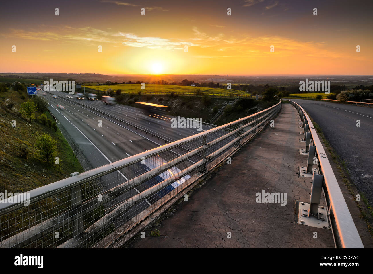 The sun sets over the Wiltshire town of Swindon as the rush hour traffic starts to paint light trails along the M4 Motorway. Stock Photo