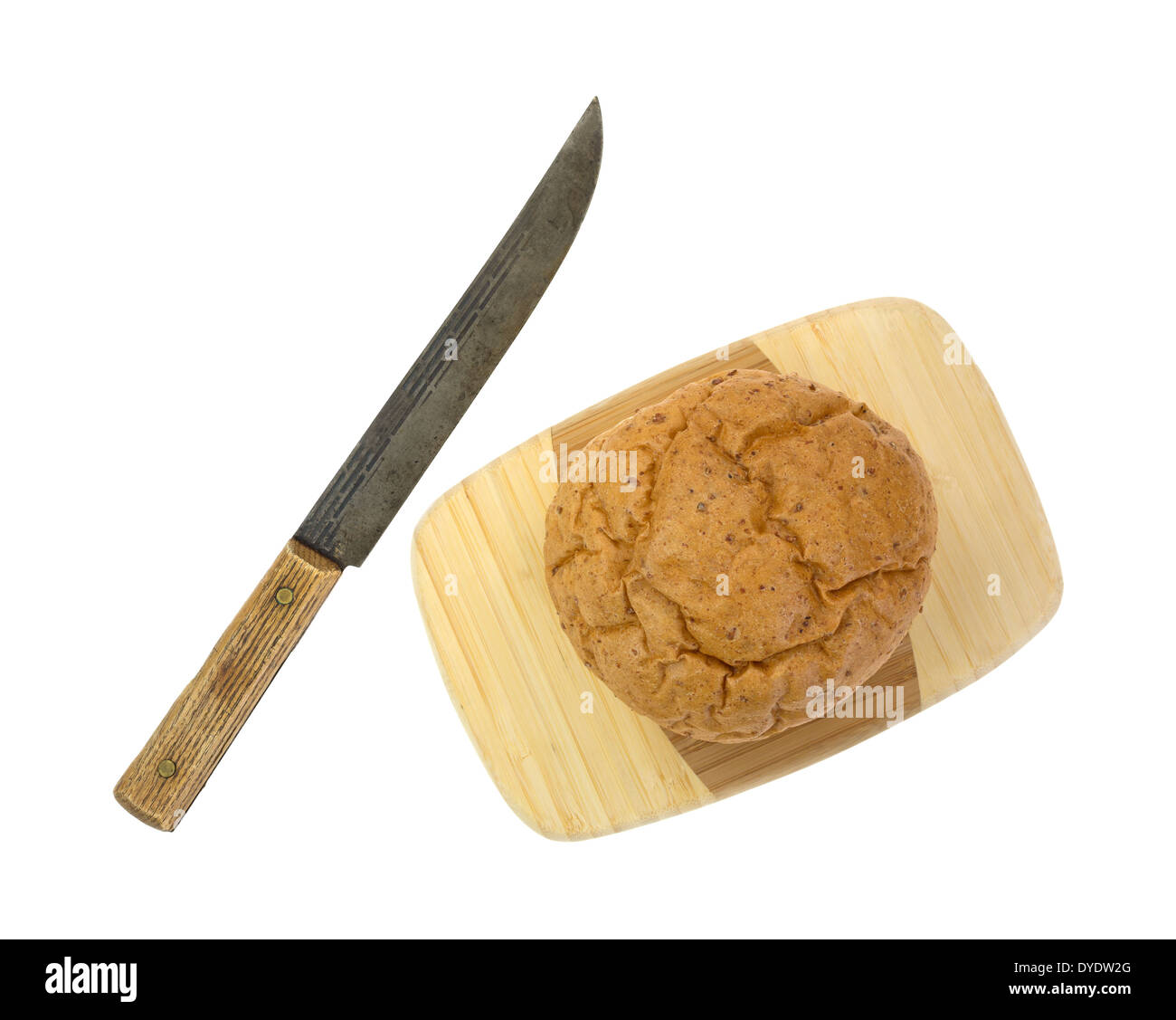 A small whole wheat boule bread on a wood cutting board with an old kitchen knife to the side. Stock Photo
