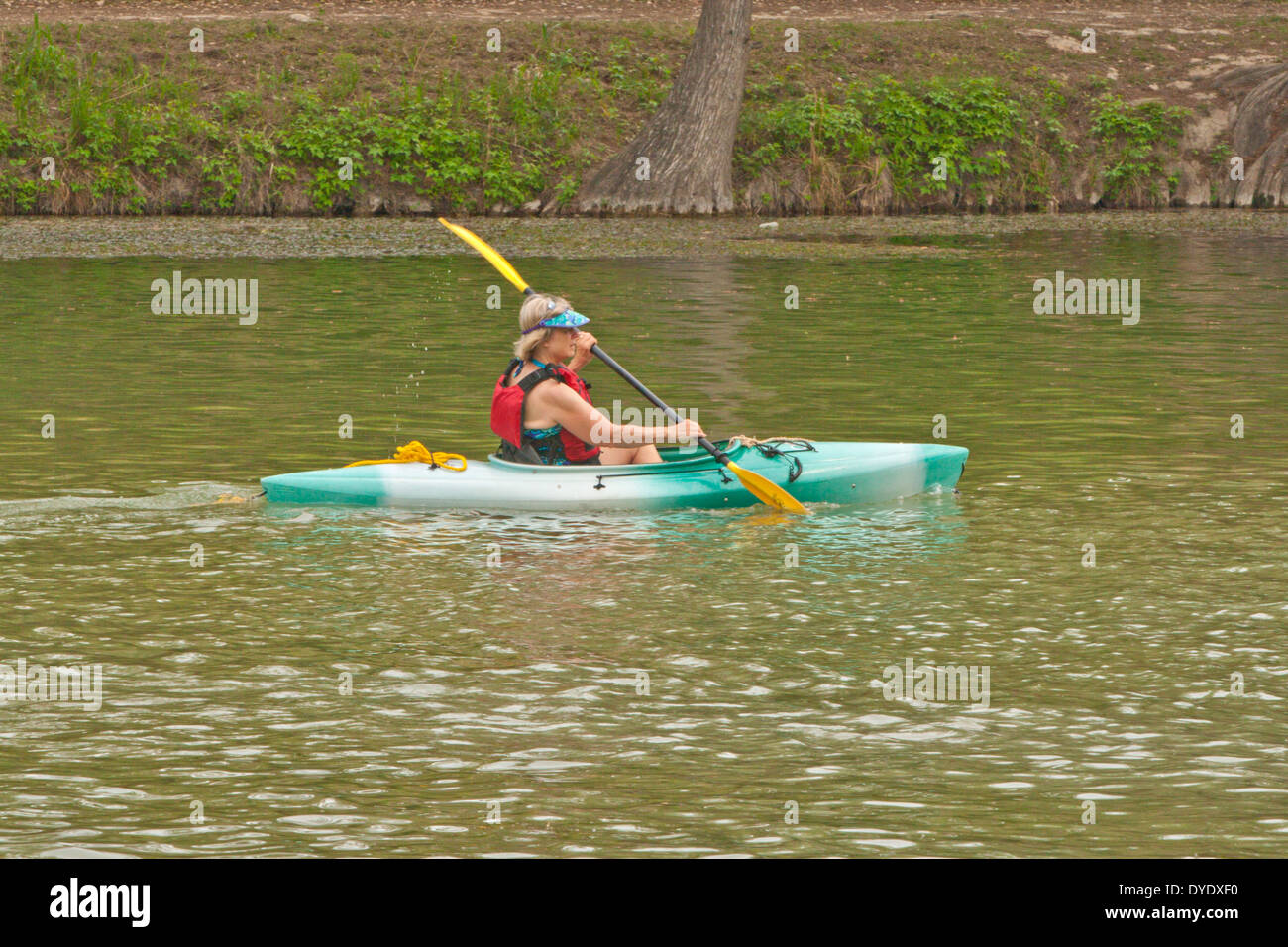 Woman wearing personal floatation device PFD paddling kayak in river